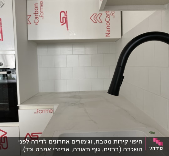 מטבח בשיפוץ עם ארונות מכוסים בניילון וברז חדש